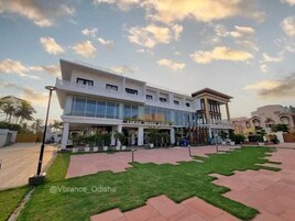 Um edifício moderno com telhado plano, grandes janelas e um pátio pavimentado com grama.