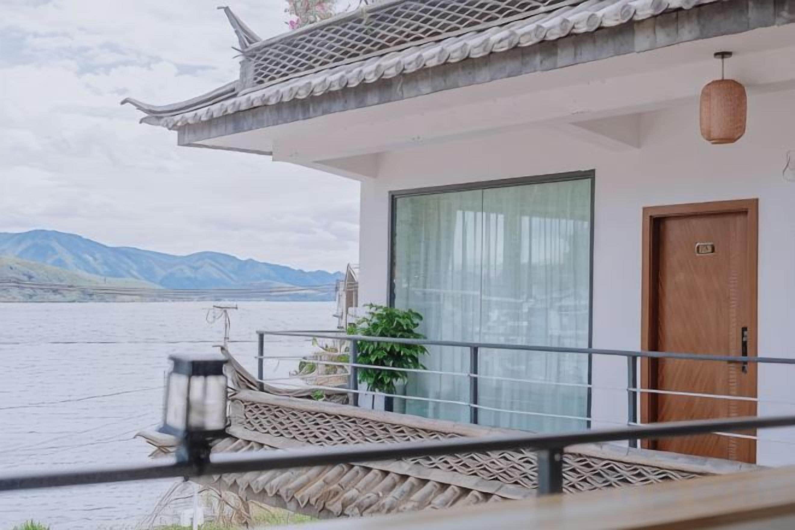 Un edificio tradicional con un balcón que da a un cuerpo de agua y montañas.