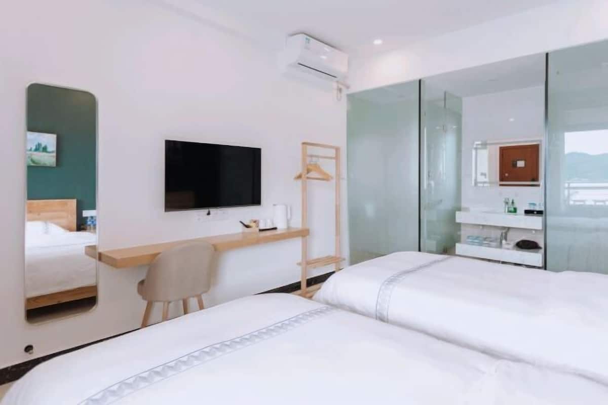 A modern hotel room with a bed, a desk, a chair, a television, and a mirror.