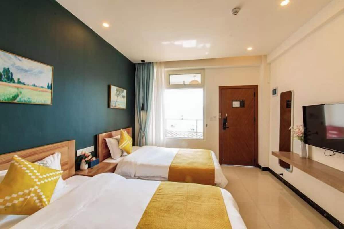 A hotel room with two beds, a TV, a door, and a window.