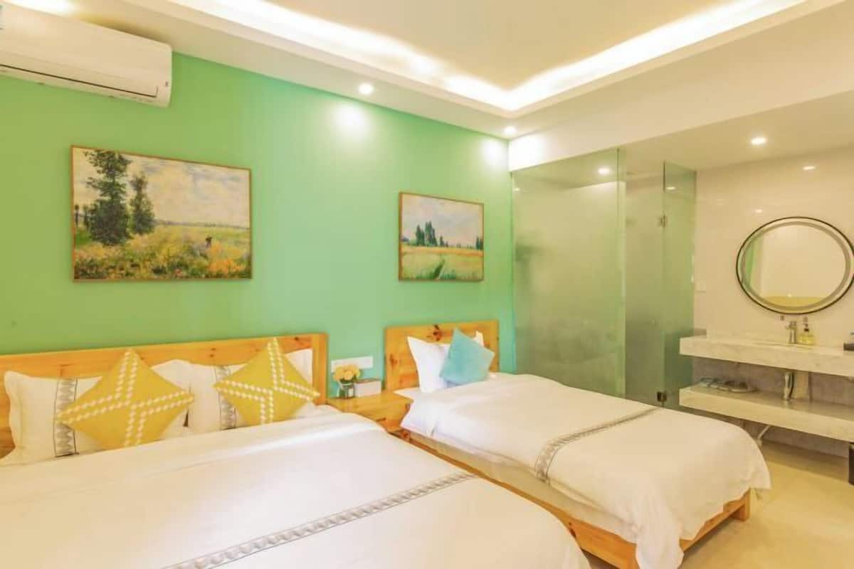 A hotel room with two beds, green walls, and artwork.