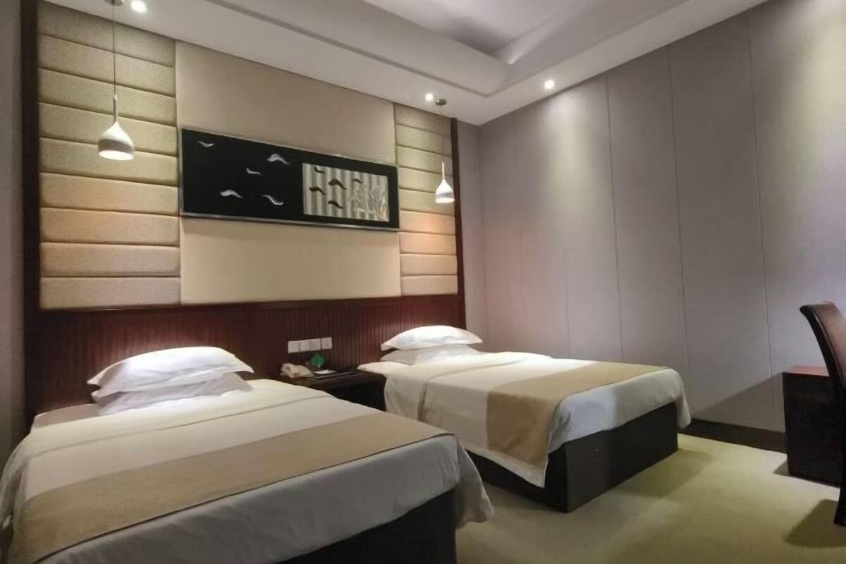 Una habitación de hotel con dos camas, una obra de arte grande en la pared y una lámpara moderna.