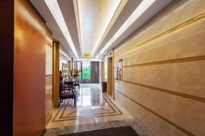 A hotel corridor with a marble floor, a reception desk, and a view of the outdoors. - Hengrong Holiday Hotel (Chongqing)