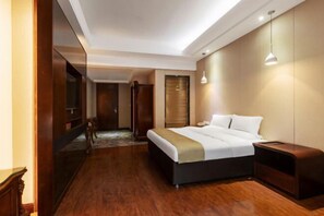 A modern hotel room with a large bed, wooden flooring, a desk, and a TV. - Hengrong Holiday Hotel (Chongqing)