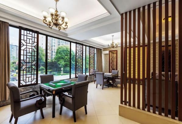 A room with a pool table, comfortable seating, and large windows offering a view of greenery and buildings. - Hengrong Holiday Hotel (Chongqing)