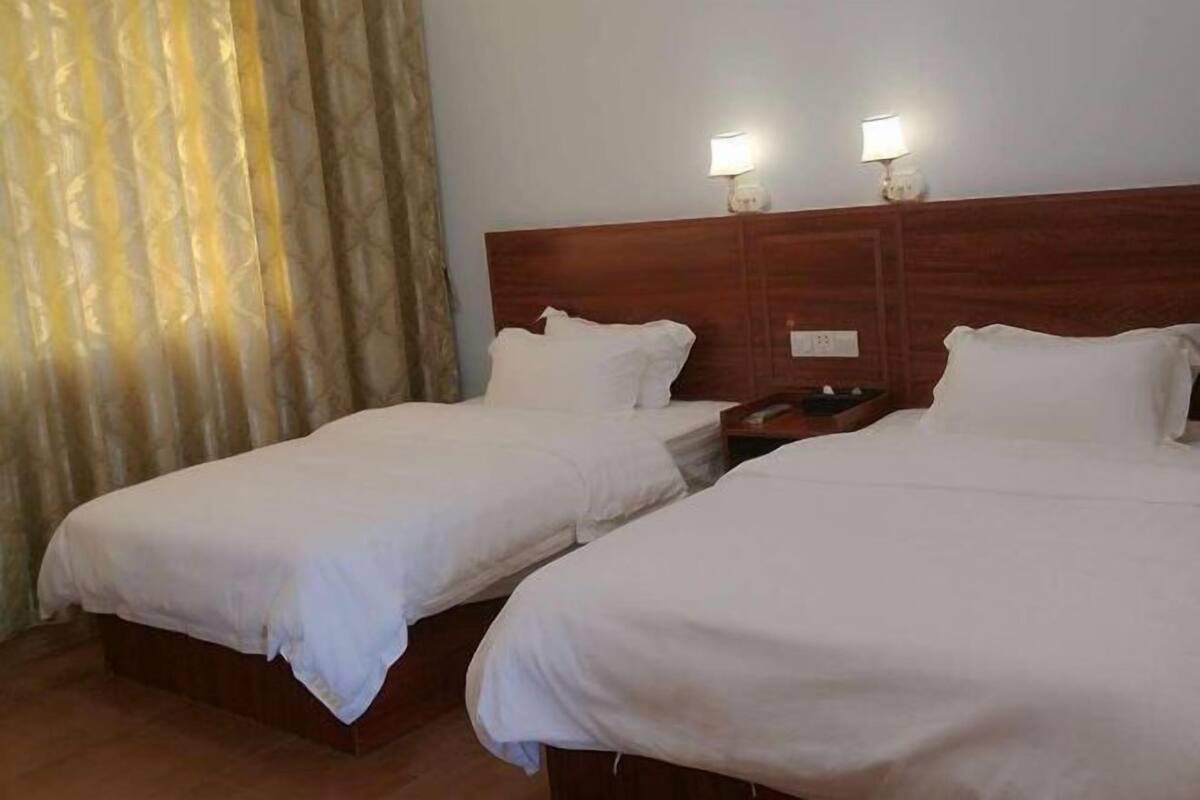 Two single beds with wooden headboards, a nightstand, and two wall-mounted lamps.