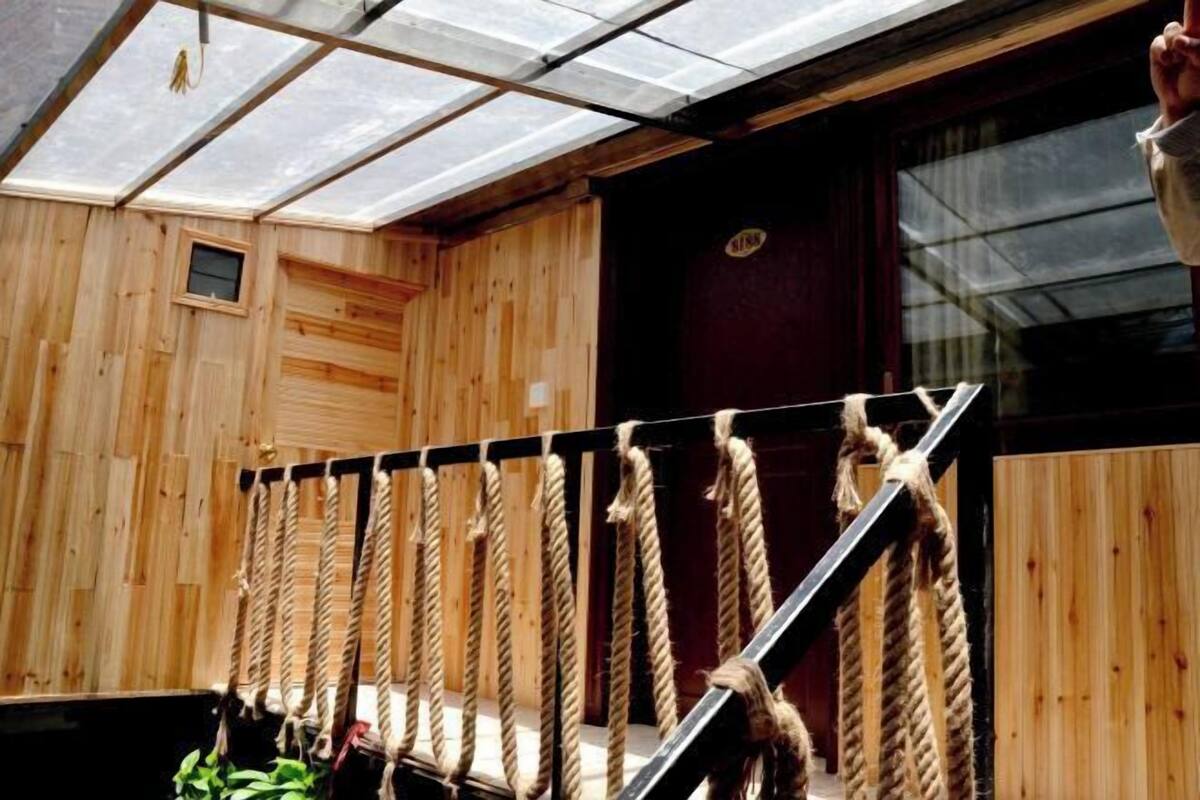 A wooden interior with a rope staircase, a small window, and a door with a sign.