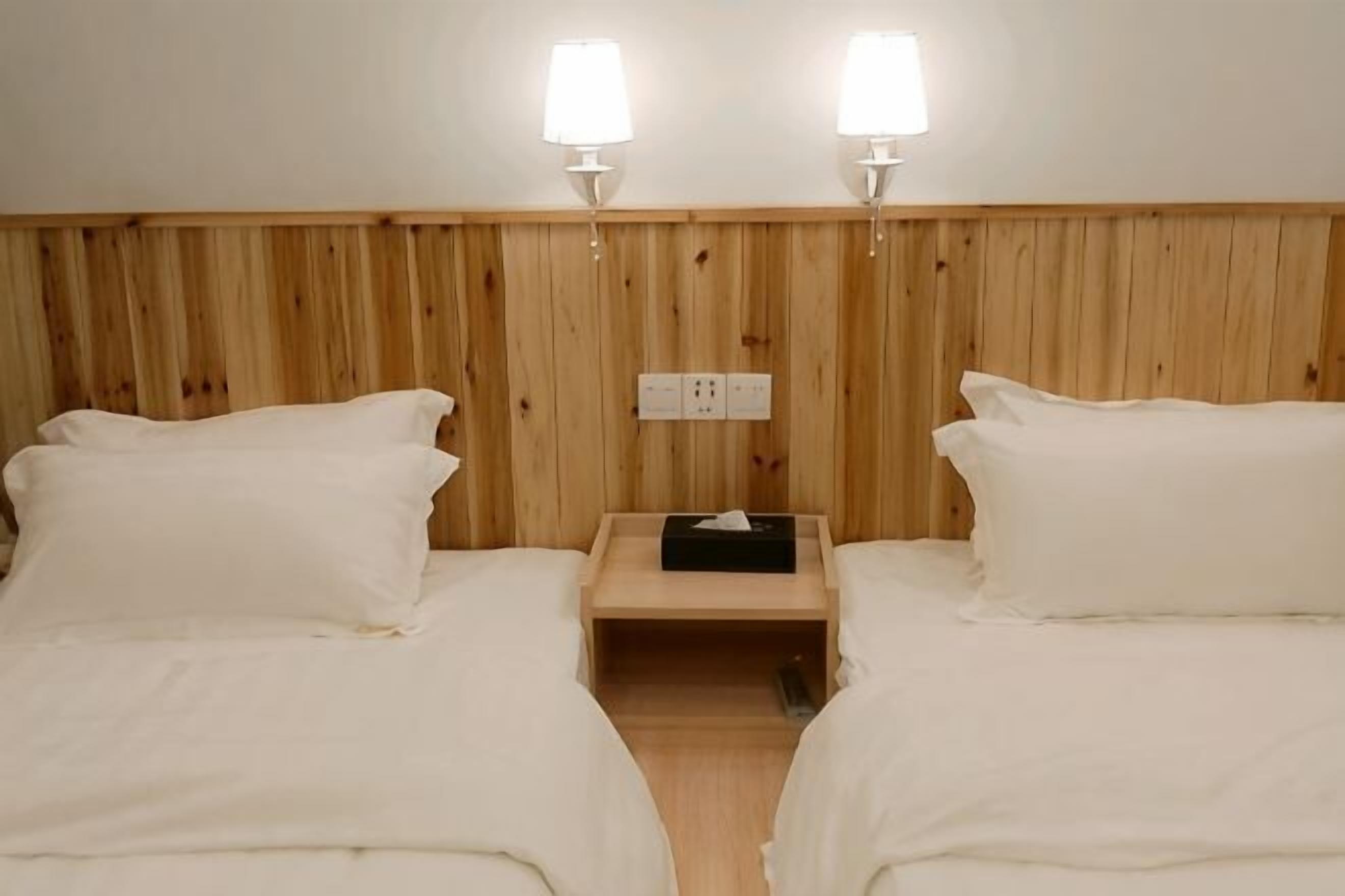 Una camera da letto con due letti, una testiera in legno, lampade sui comodini e un comodino con lampada.