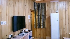 A wooden-paneled room with a flat-screen TV, a white refrigerator, and a door with a patterned curtain. - Meilaiya Hotel Huangyao Ancient Town (Zhaoping)