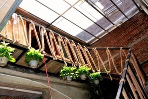 Una habitación con tragaluces, plantas colgantes y una pared de ladrillo.