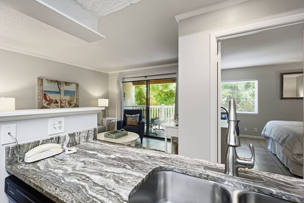 A modern kitchen with a marble countertop, a built-in oven, and a sink.
