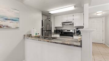 A modern kitchen with white cabinets, stainless steel appliances, and a marble countertop.