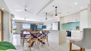 A modern kitchen with white cabinets, a central island, and pendant lighting. - Skytower Wonder Oceanview Balcony - Pool - Office (Darwin)