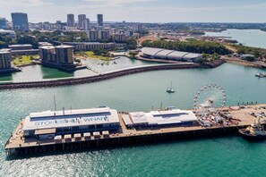 A waterfront hotel with a Ferris wheel, a pier, and a cityscape in the background. - Skytower Wonder Oceanview Balcony - Pool - Office (Darwin)