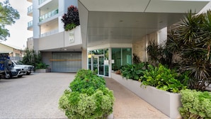 A modern building with a covered entrance, a garage, and a parking area with a truck. - Skytower Wonder Oceanview Balcony - Pool - Office (Darwin)