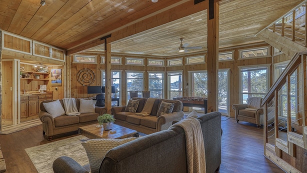 A spacious living room with wooden beams, large windows, and a cozy fireplace.
