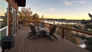 A wooden deck with outdoor furniture overlooking a lake.
