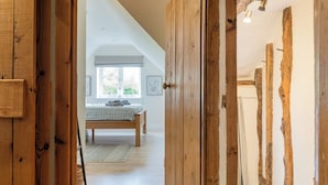 A bedroom with a wooden door, a bed, a window, and a framed picture on the wall. - Clifford Chambers Cosy 2 Bedroom Cottage (Stratford-upon-Avon)
