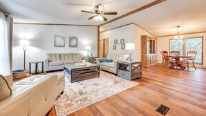 A spacious living room with a large sofa, a coffee table, and a dining area with a wooden table and chairs. - Relax, Swim & Explore: Home in Wimberley! (Wimberley)