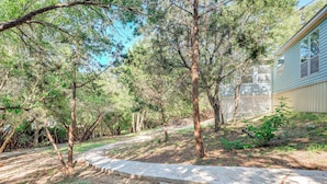 A pathway leading to a house surrounded by trees. - Relax, Swim & Explore: Home in Wimberley! (Wimberley)