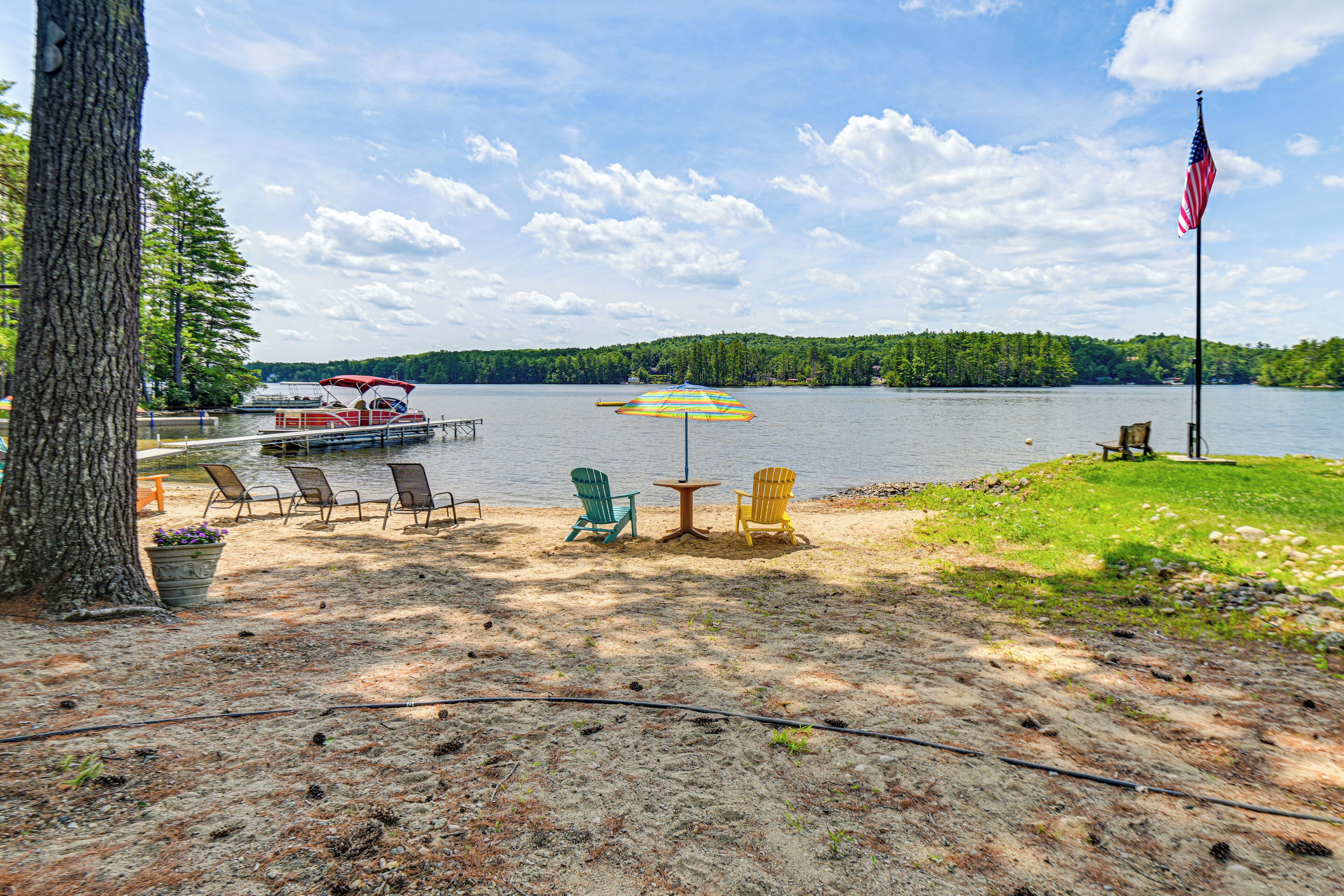 A lakeside setting with a dock, chairs, and an American flag.