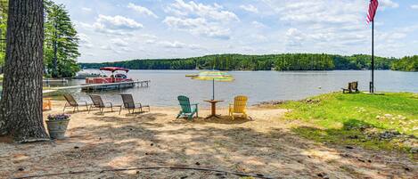 A lakeside setting with a dock, chairs, and an American flag.