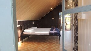 Un dormitorio con techo de madera, una cama, una mesita de noche y una ventana.