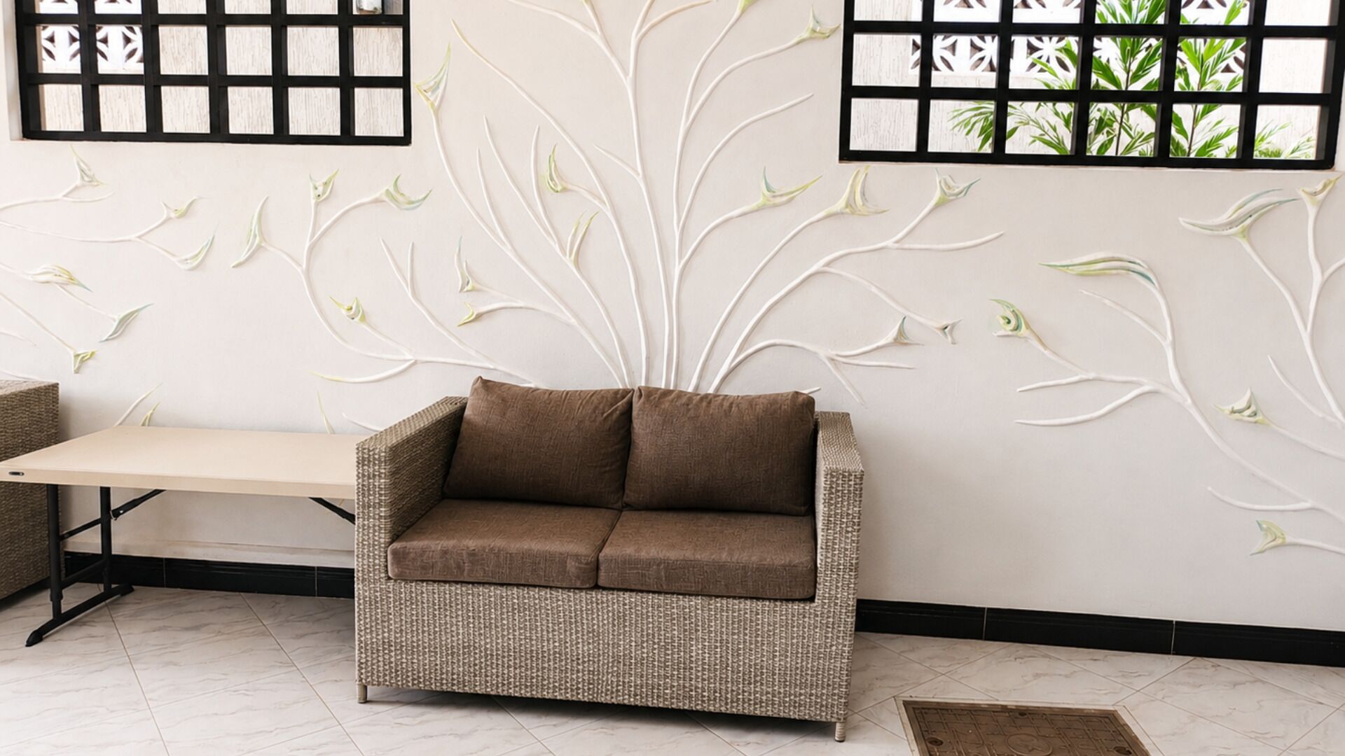 Un sofá de mimbre en una habitación con un diseño de árbol decorativo en la pared.
