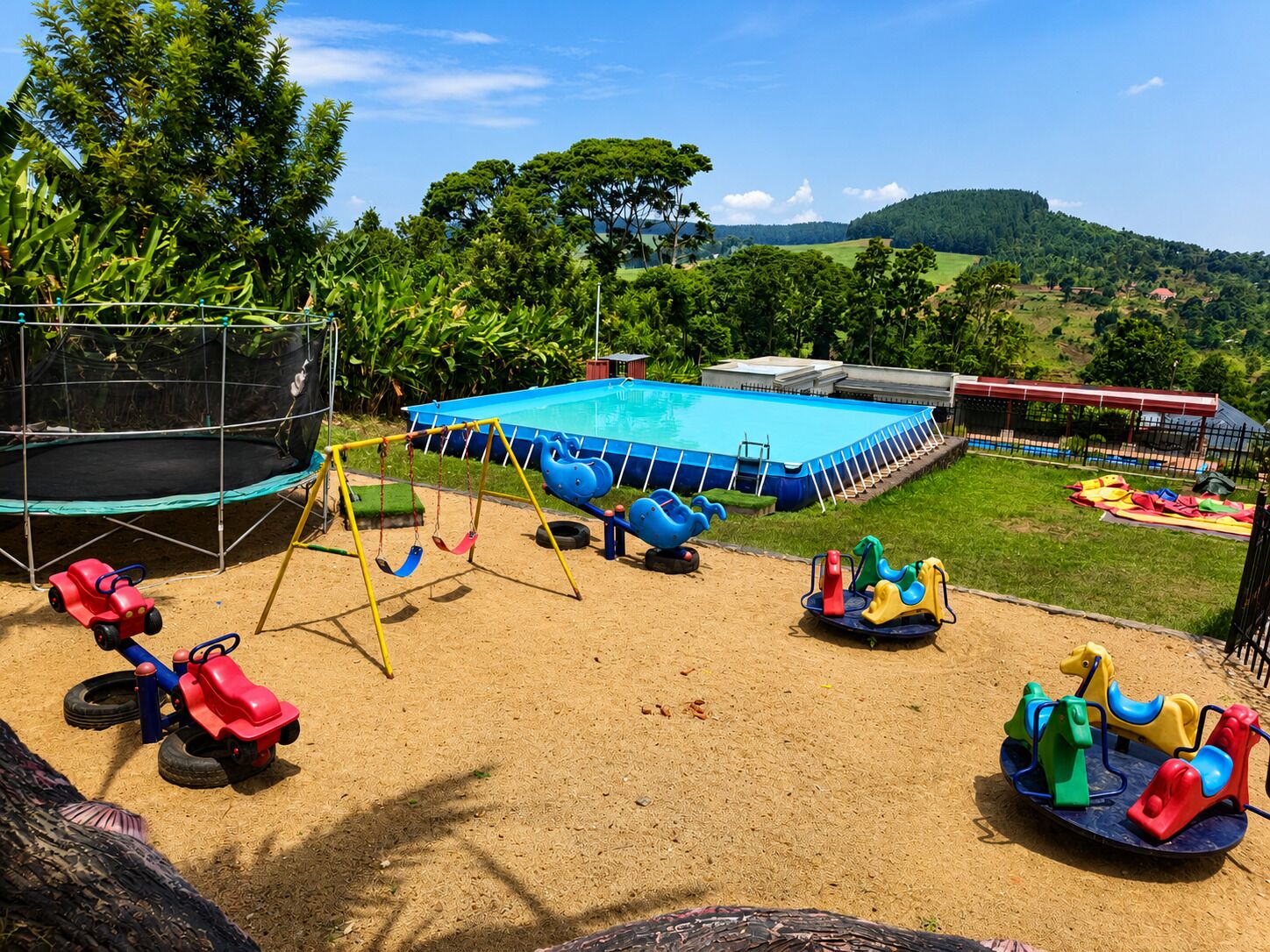 A playground with a trampoline, swings, and a pool.