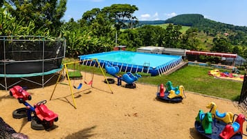 A playground with a trampoline, swings, and a pool.