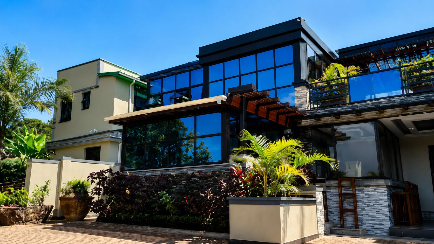 A modern two-story house with large windows, a balcony, and a well-maintained garden.