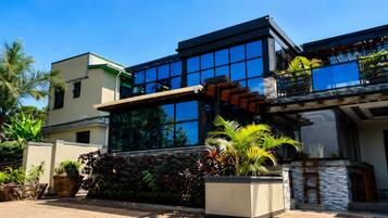 A modern two-story house with large windows, a balcony, and a well-maintained garden.