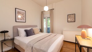 A modern bedroom with a bed, bedside tables, and artwork on the walls. - Green Oasis 2BR Apartment in Pangrati (Athina)