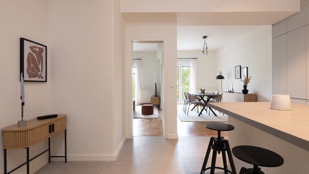 A modern kitchen with a bar area, a dining table, and a view into the dining room. - Green Oasis 2BR Apartment in Pangrati (Athina)