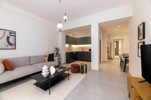 Een moderne woonkamer met een bank, salontafel en een eethoek met stoelen en een tafel.