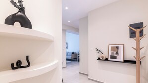 Un intérieur moderne avec des murs blancs, un porte-manteau en bois et un tableau encadré posé sur une étagère.