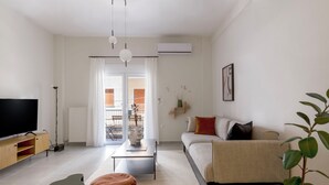 Un salon moderne avec un téléviseur à écran plat, un canapé, une table basse et une plante en pot.