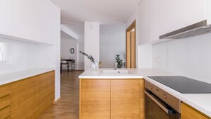 Una cocina moderna con armarios de madera, horno empotrado y placa de inducción negra.