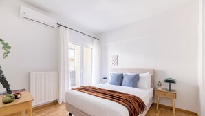 Un dormitorio con cama, mesita de noche, lámpara y ventana con cortinas.