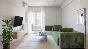 Una sala de estar moderna con un televisor de pantalla plana, un sofá verde, una mesa de centro y una planta en maceta.