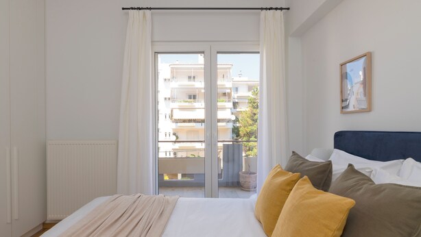 Un dormitorio con una cama grande, vistas a un balcón y un cuadro en la pared.