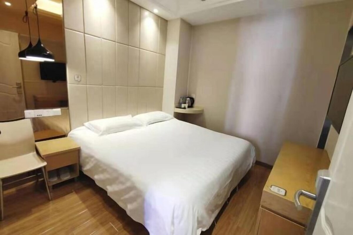 Una habitación de hotel moderna con una cama grande, mesitas de noche, un escritorio y una pequeña zona de estar.