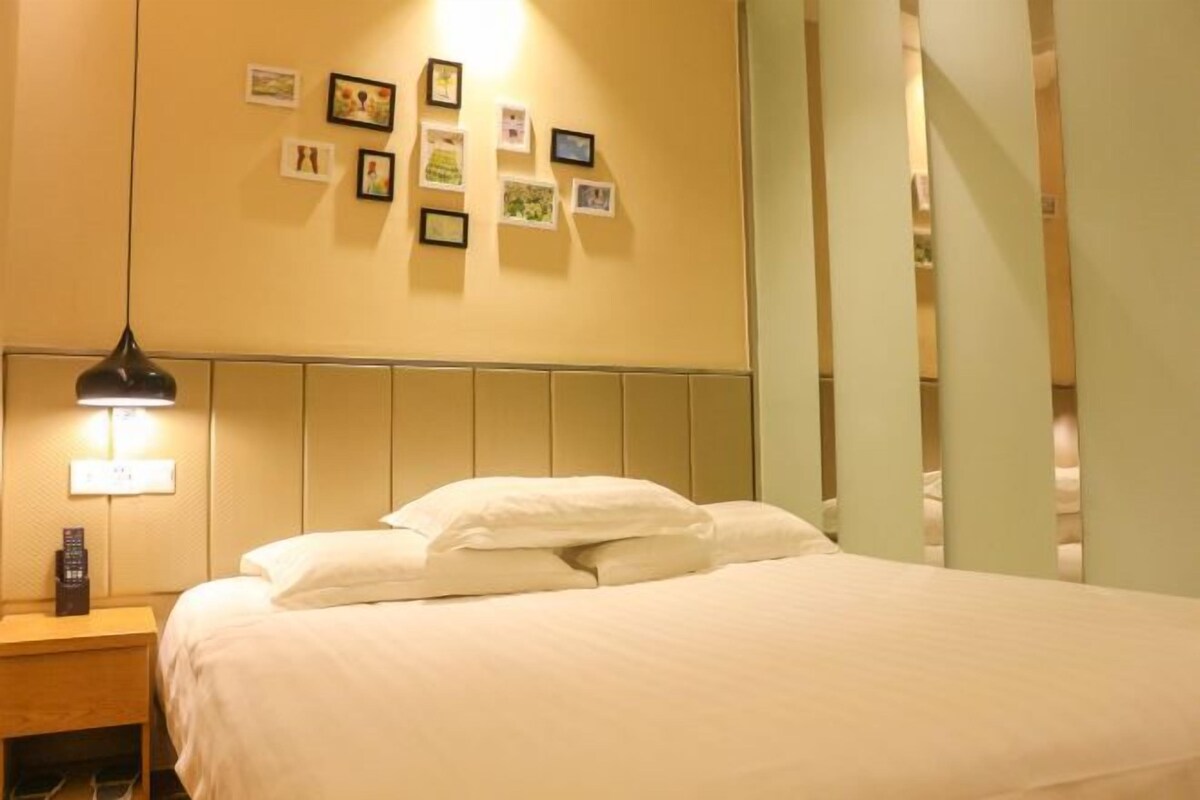 Una habitación de hotel con una cama, una mesita de noche, una lámpara y un cuadro en la pared.