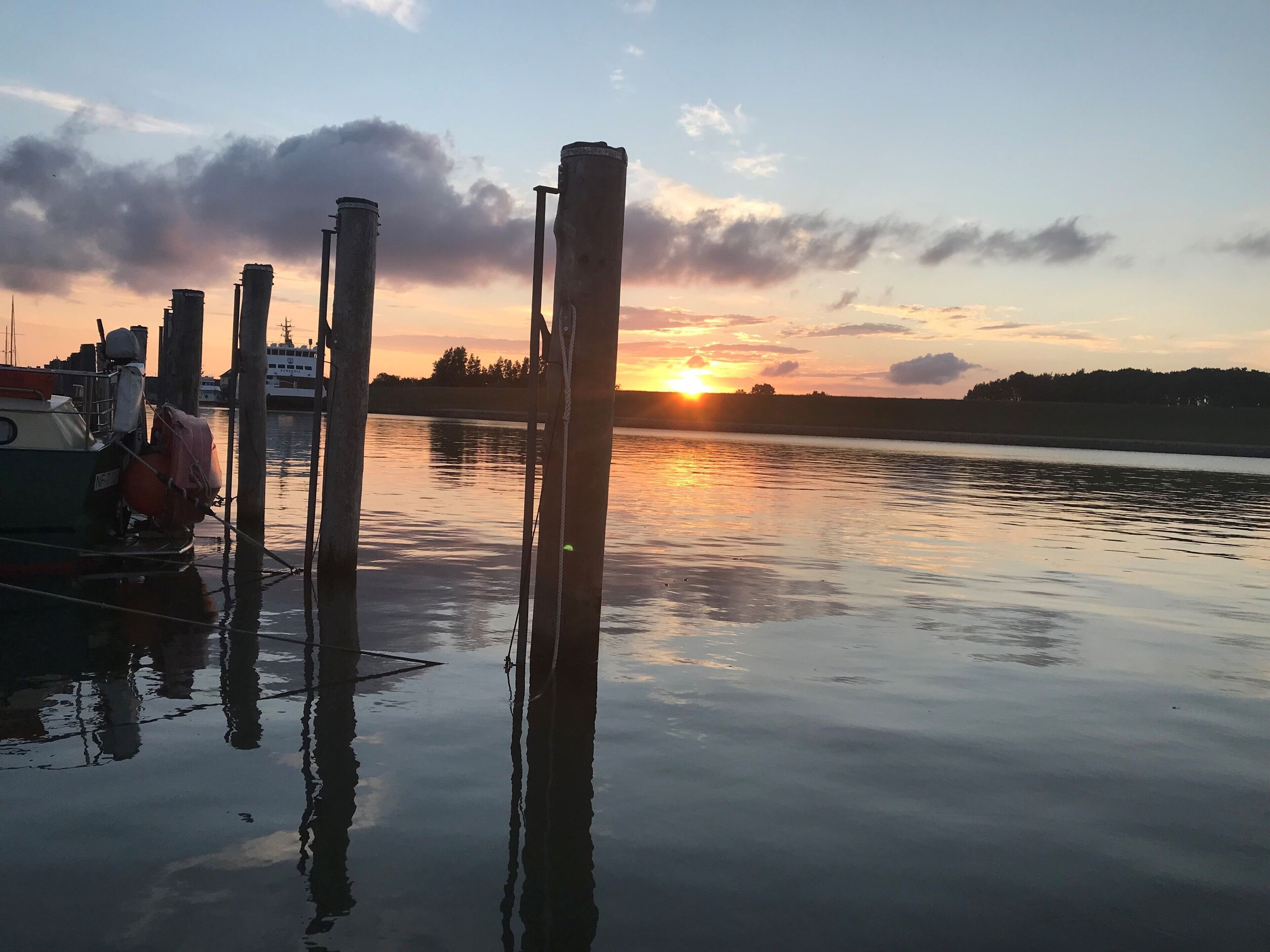 Una masa de agua tranquila con barcos amarrados y postes de madera.