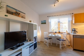 A modern kitchen with a dining area, a television, and a coffee machine.