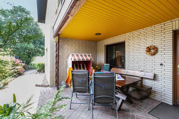 A patio area with a brick wall, a yellow ceiling, and a wooden table with chairs.