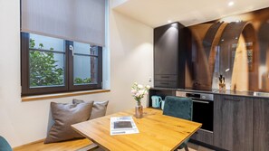 A modern kitchen with a wooden table, a vase with flowers, and a window with blinds. - Premium Apartment 'Fässle' with Private Terrace, Shared Garden and Wi-Fi (Reichenau)