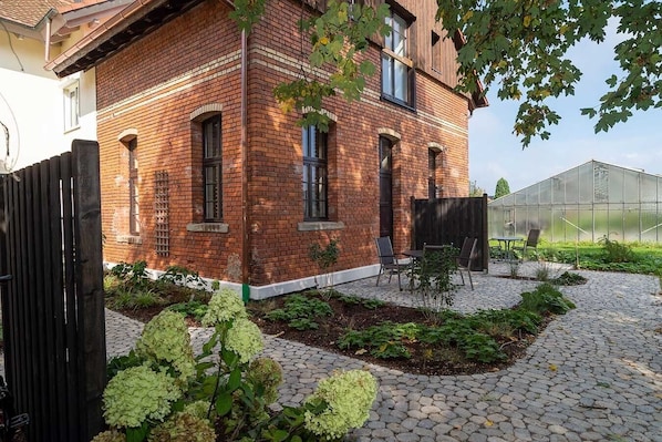 A brick house with a garden patio, a greenhouse, and a black gate. - Premium Apartment 'Fässle' with Private Terrace, Shared Garden and Wi-Fi (Reichenau)