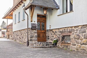 A stone building with a wooden door and steps leading to a porch. - Apartment 'Zur Alten Post' with Shared Garden and Wi-Fi (Ulrichstein)