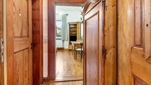 Een houten gang met een deur die leidt naar een kamer met een eettafel en stoelen.
